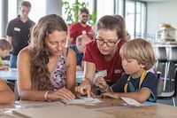 3 Personen experimentieren an einem Tisch