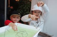 2 Kinder experimentieren mit Seifenblasen und eckigen Drahtformen