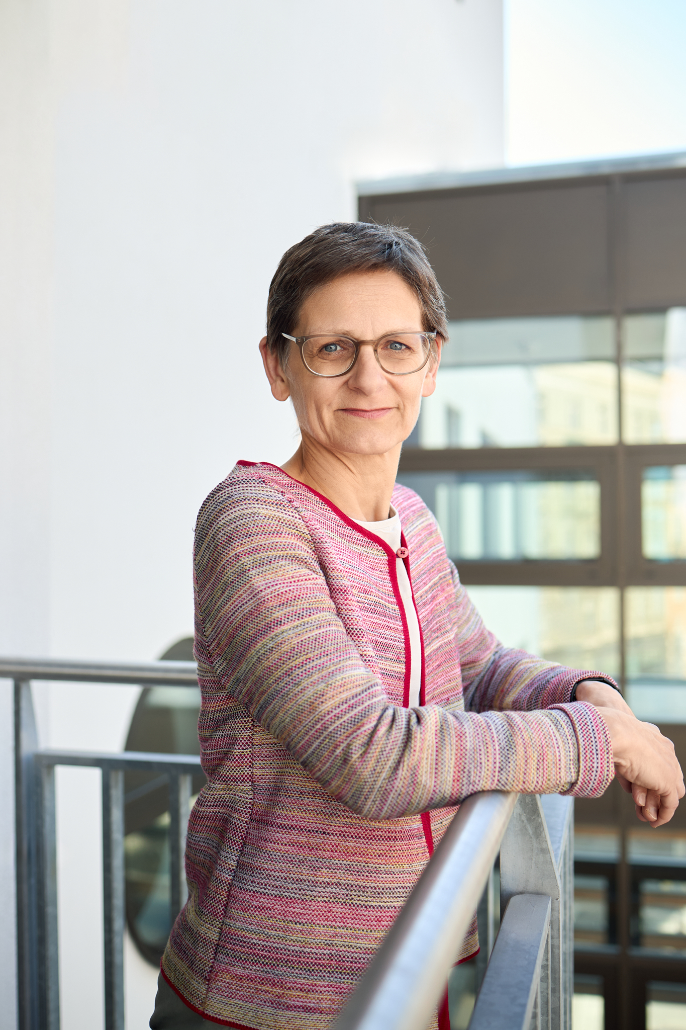 Eine Person, Doris Erhard, lehnt am Geländer und blickt in die Kamera.